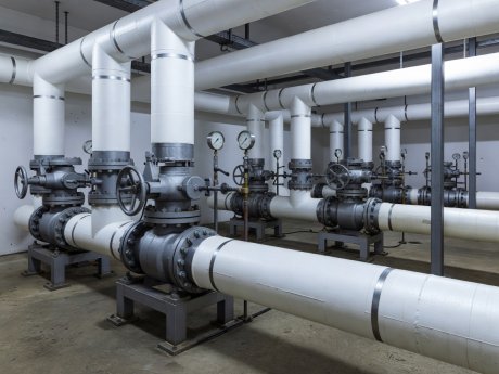 Industrial refrigeration plant room showing insulated suction headers, pressure gauges, and labeled valve stations