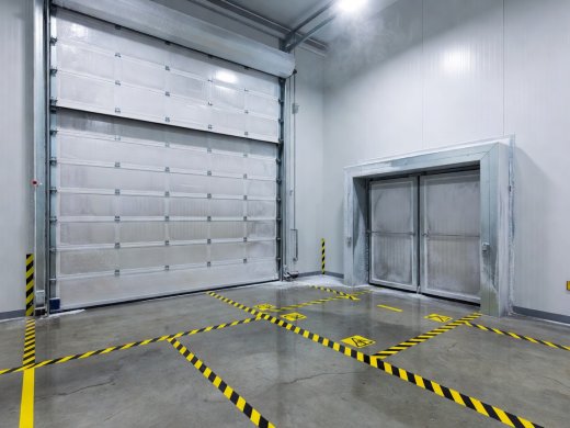 High-speed insulated rapid-roll door and airlock vestibule inside a sub-zero warehouse with floor boundary markings